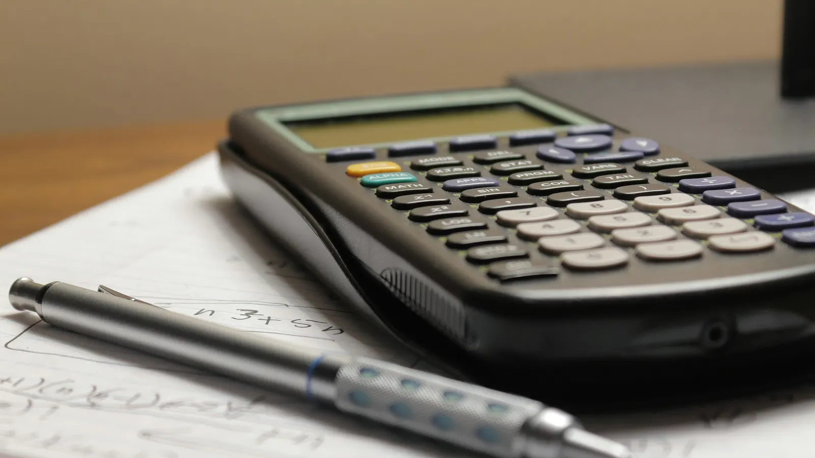 Calculator and pen resting on a sheet of paper