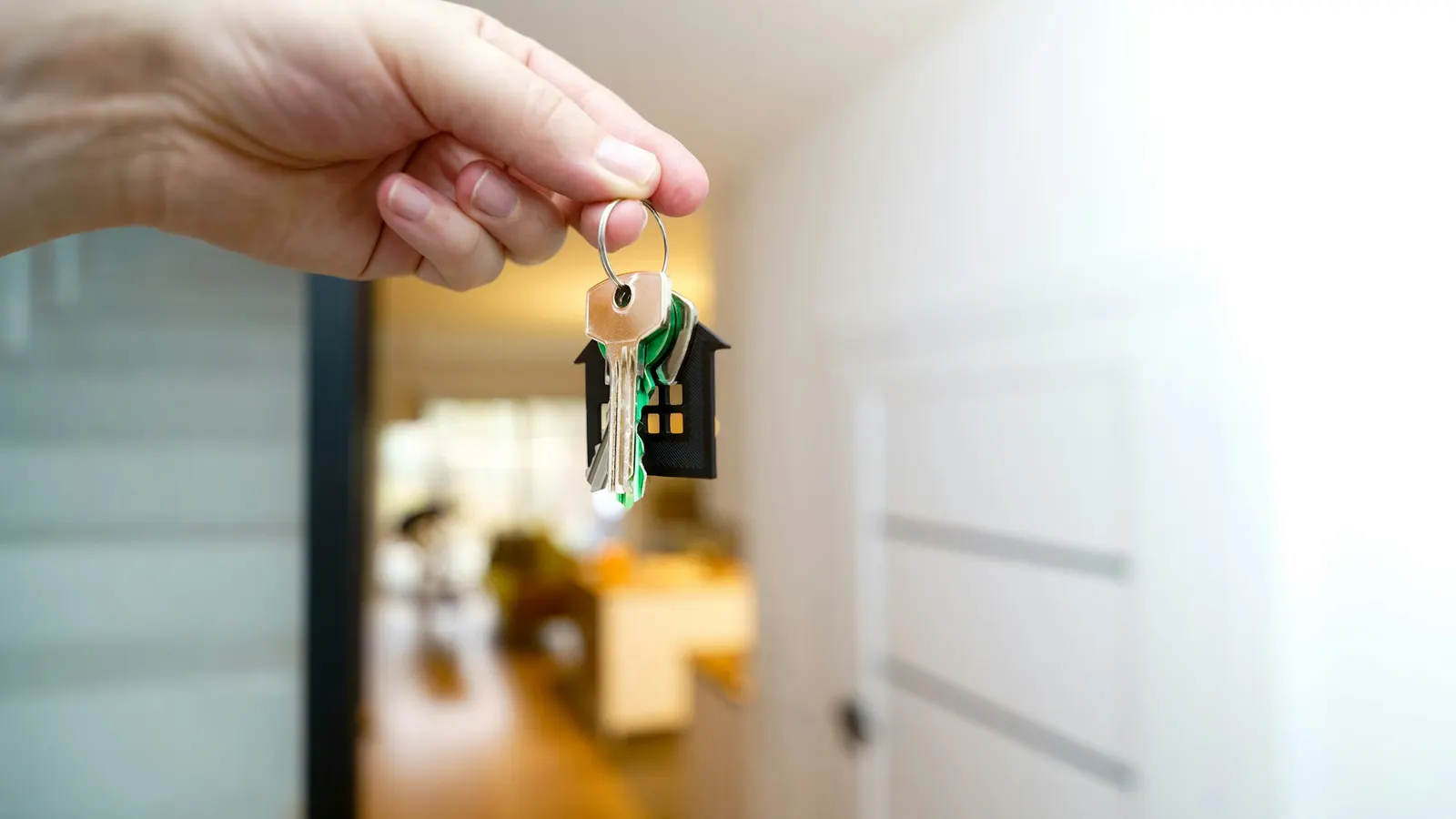 Hand holding house keys in front of a front door