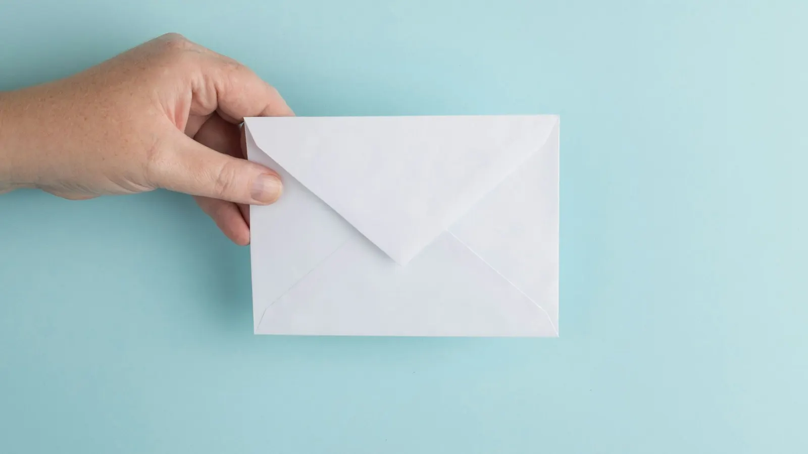 Hand holding out a white envelope