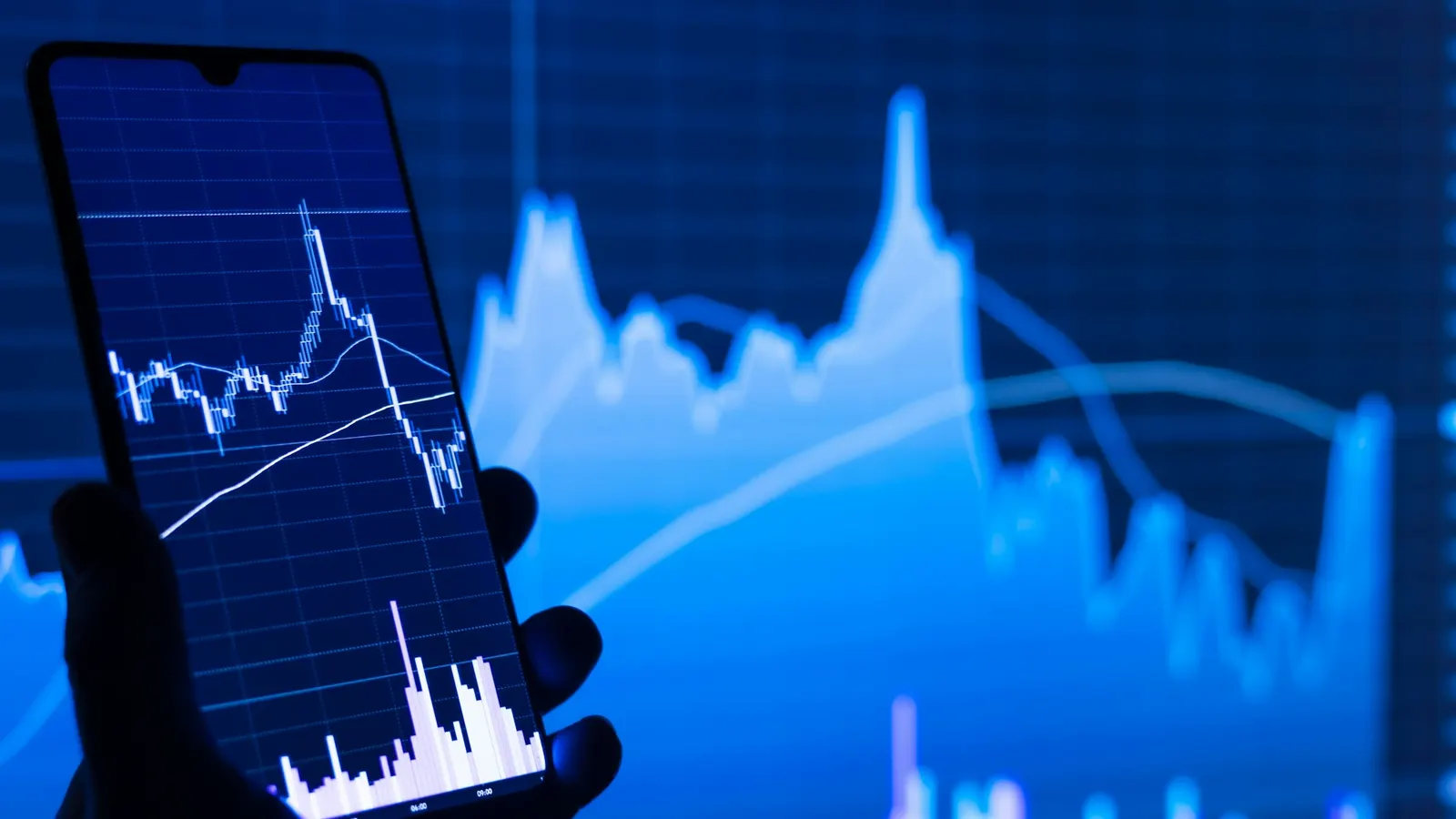 Person holding a phone in front of a share price chart