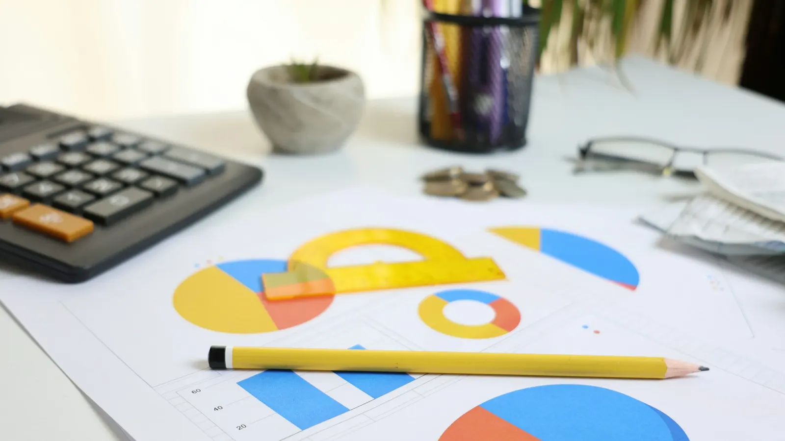 Desk with a calculator, printed charts and a pencil
