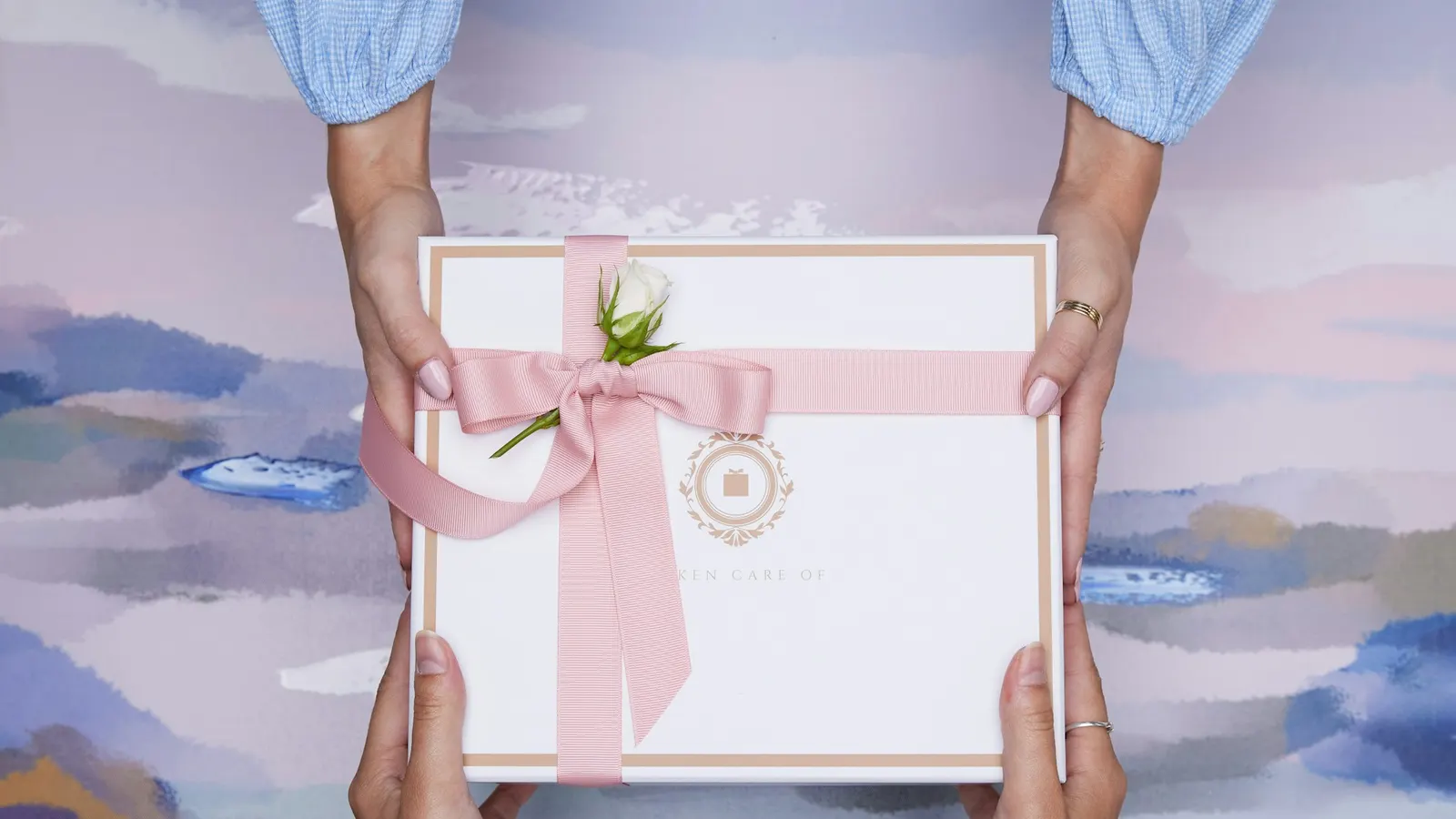 Two hands passing a wrapped gift box