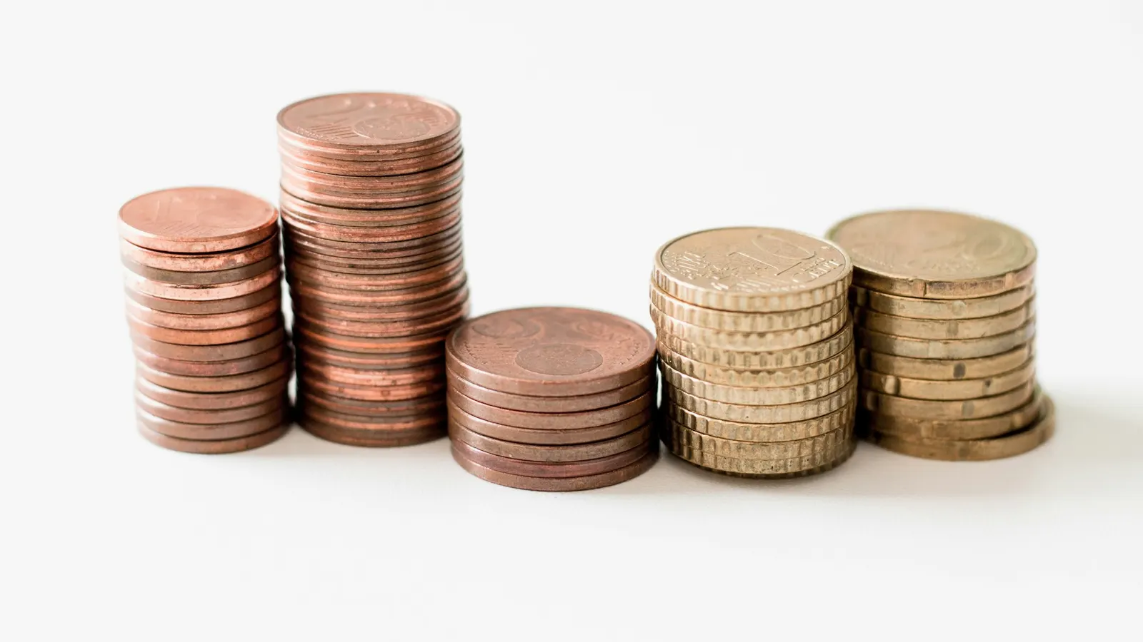 Stacks of gold-coloured coins on a white surface