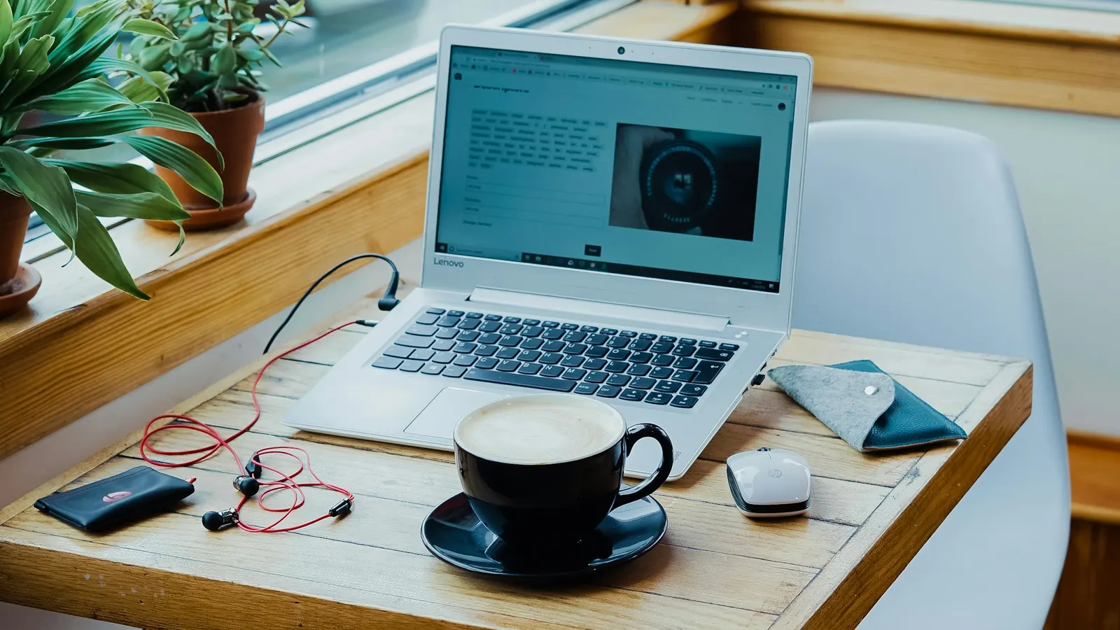 Laptop, coffee cup and earphones on a wooden desk