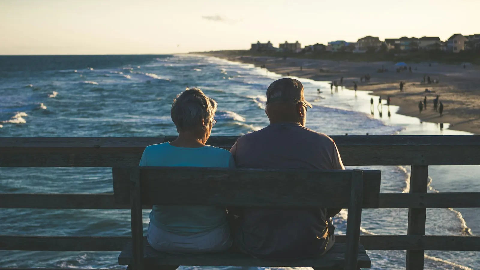 Couple sitting on a bench looking out at the beach