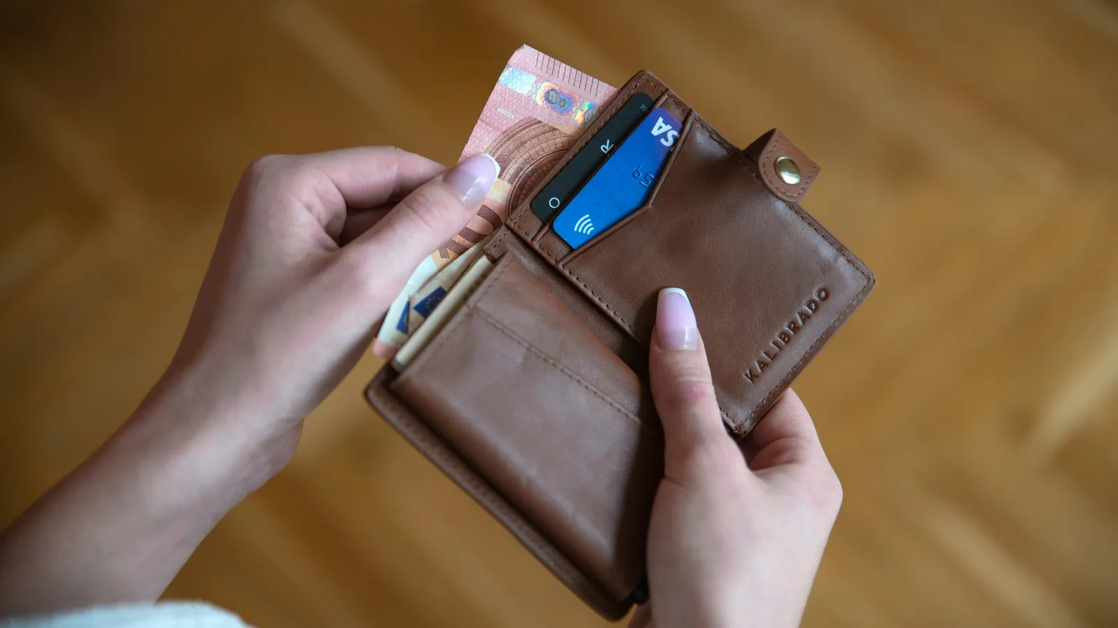 Person holding a brown leather card wallet